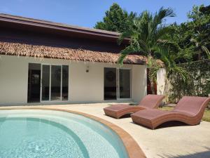 una piscina con due sedie e una casa di Superb pool villa 5 bedrooms a Baan Tai