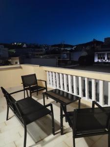 drie stoelen en een tafel op een balkon bij Captain's Mermaid Houses, Karpathos in Karpathos