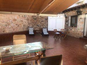 a room with chairs and tables and a stone wall at La casita in Baños de la Encina