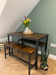 a table with a bench and a vase with flowers at Cherry Blossom cottage in Old Glossop