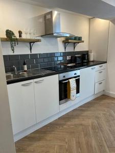 Una cocina blanca con fregadero y estufa. en Cherry Blossom cottage, en Old Glossop 36 fotos más