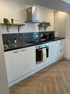 a white kitchen with a sink and a stove at Cherry Blossom cottage in Old Glossop