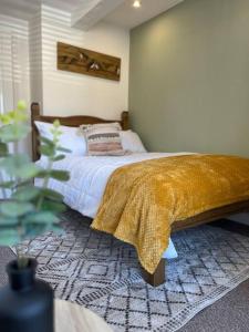 a bedroom with a bed with a gold blanket on it at Cherry Blossom cottage in Old Glossop