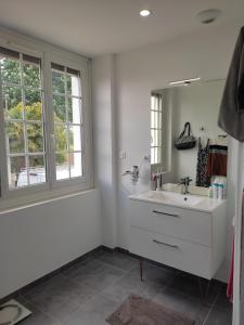 Baño blanco con lavabo y espejo en Chambre Ruaudin, en Ruaudin
