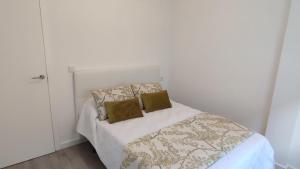 a white bedroom with a bed with two pillows at Apartamentos Plateria in O Grove +10 photos