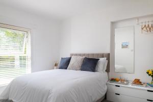 a white bedroom with a white bed and a mirror at Bron Eryri - Our Cosy House opposite the entrance to Portmeirion! in Mynfford