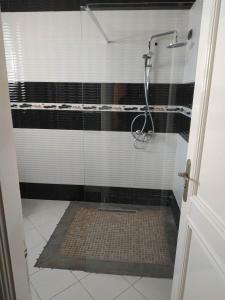 a shower with a black and white tiled bathroom at LE JASMIN RESIDENCE bord de mer in Hammam Sousse