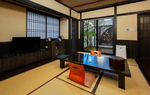 a living room with a wooden table and a tv at Bettei Soan in Minami Aso
