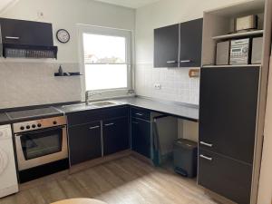 a kitchen with black cabinets and a sink and a window at Ferienwohnung Friedrich Dorfmark in Bad Fallingbostel +15 photos