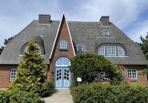 a house with a gray roof and a blue door at Strandkoje in Nebel +19 photos