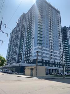 un gran edificio alto con coches estacionados frente a él en Sky apartments Budova en Odesa