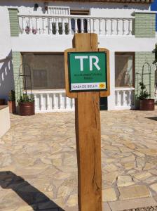 un panneau sur un poteau en bois devant un bâtiment dans l'établissement Casa de Bello, à Tortosa