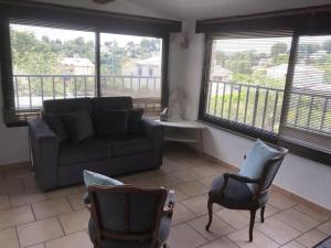 a living room with a couch and chairs and windows at Petite Maison de Charme in Vence