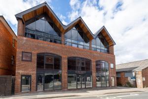 a red brick building with a wooden roof at Mustafa House By E2M Stays - 1 & 2 Bedroom Stunning Apt in Central Town in Camberley