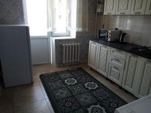 a kitchen with white cabinets and a rug on the floor at Гостевой Дом in Qyzylorda