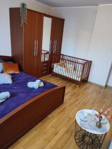 a bedroom with a bed and a crib and a table at Apartament nad Nidą in Sobków