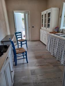 a kitchen with white cabinets and blue chairs and wooden floors at Magi - Violetta in Ponza