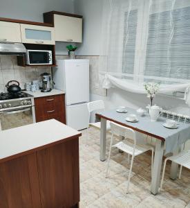 a kitchen with a table and a white refrigerator at Apartament nad Nidą in Sobków