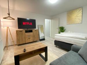 een woonkamer met een bed en een tv op een dressoir bij LUXOMES: Design Apartment - private Parking - 4 People in Ingolstadt