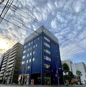 a large blue building on a city street at WISE OWL HOSTELS SAPPORO in Sapporo