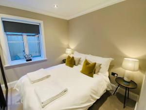 een slaapkamer met een wit bed met gele kussens en een raam bij Jubilee apartment, Winchester in Winchester