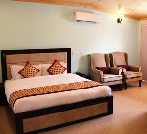 une chambre avec un grand lit et deux chaises dans l'établissement Four Banyans Spirit & Nature Resort, à Rāipur 50 autres photos