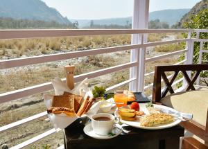 une table de petit-déjeuner avec des aliments pour le petit-déjeuner et du café, et une fenêtre dans l'établissement Four Banyans Spirit & Nature Resort, à Rāipur