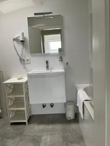 W białej łazience znajduje się umywalka i lustro. w obiekcie City Flat gegenüber Kurhaus, Zentrum Freudenstadt w mieście Freudenstadt