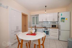 uma cozinha branca com uma mesa e cadeiras brancas em Apartment Marina em Okrug Donji