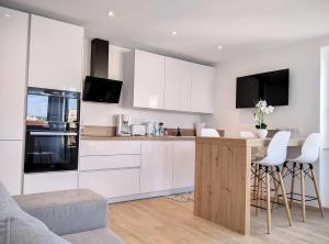 kuchnia z białymi szafkami i bar z stołkami w obiekcie Résidence Graziella Appartement 621 w mieście Juan-les-Pins