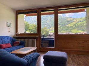 a living room with a blue couch and a large window at Apartement Karen TOP 35 - by Four Seasons Apartments in Kaprun
