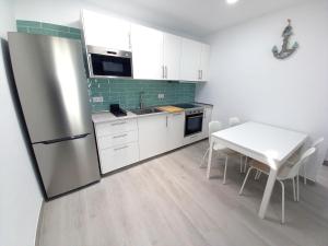 a kitchen with a refrigerator and a table with chairs at Casa Malakita with private seaview roof terrace in Conil de la Frontera
