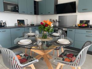 a kitchen with a glass table with chairs and flowers at Appartement lumineux rénové à neuf in Saint-Pierre +11 photos