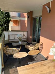 un patio con 2 mesas y sillas en un balcón en « Le Andrea », en Cavalaire-sur-Mer