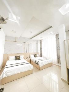 two beds in a room with white walls at Hồng Tâm Hotel in Da Lat