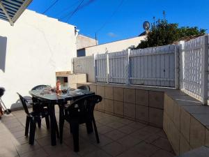 einen Tisch und Stühle auf einer Terrasse mit einem Zaun in der Unterkunft Maison cosy au centre de La Brée-les-Bains avec 4 couchages, proche plage, WiFi gratuit - FR-1-246A-219 in La Brée-les-Bains