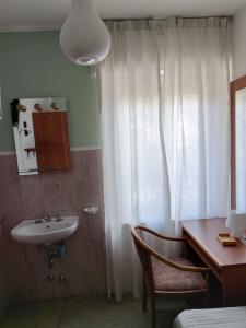 a bathroom with a sink and a desk and a window at La Maison in Aymavilles