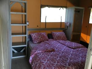 um quarto com uma cama com um edredão roxo em Camping rural la Masia em Cocentaina