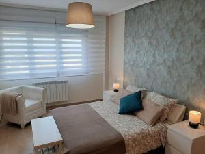 a bedroom with a large bed and a chair at APARTAMENTO PLAYA FOZ in Foz