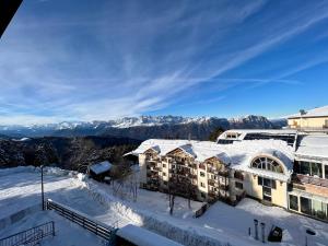 um resort na neve com montanhas ao fundo em B&B CHALET NICOLUSSI em Trento