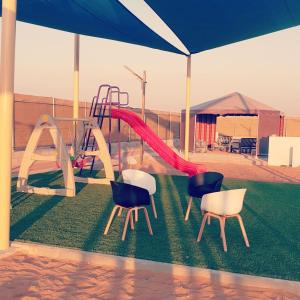 - une aire de jeux avec 2 chaises et un toboggan dans l'établissement afnan farm, à Al Ḩamrānīyah