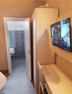 リミニにあるホテル ロイヤル プラザ の壁にテレビとテーブルが備わる客室です。