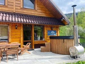 Cabaña de madera con mesa y sillas frente a ella en Domek OlimpijSki SZCZYRK en Szczyrk