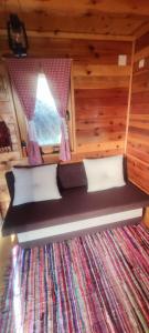 Cama en habitación con ventana y alfombra en Seoski Turizam Feniks - Vajat Ostrog, en Kosjeric
