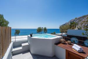 a bath tub on a balcony with the ocean in the background at Elixir Del Mar on the Beach in Kamari