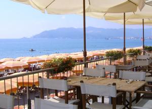 um restaurante com mesas e guarda-sóis na praia em Savona Sant'antonio Mare Clima WiFi em Savona
