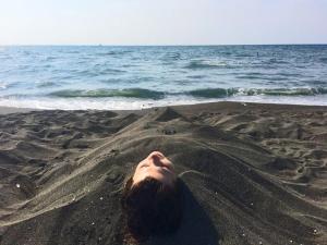 una mujer tirada en la arena en la playa en HOTEL - SHORENA en Ureki