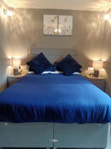 - une chambre avec un lit bleu et 2 tables de nuit dans l'établissement The Milton Bed & Breakfast, à Elgin
