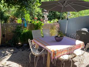 - une table et des chaises avec un parasol dans l'arrière-cour dans l'établissement La kaze manguiers, à L'Étang-Salé