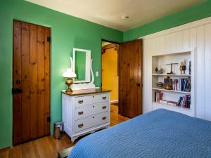 ein Schlafzimmer mit grünen Wänden, einem Bett und einem Spiegel in der Unterkunft La Vida Buena, 2 Bedrooms, Sleeps 4, Fireplace, Patio, Yard, Grill in Santa Fe